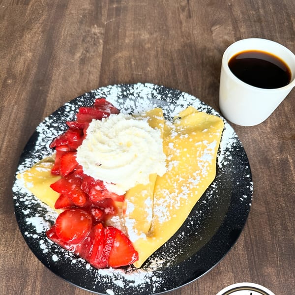 Jack's Crepes: A golden crepe with strawberries, whipped cream, and powdered sugar, with coffee.